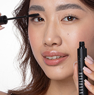 A woman is applying mascara to her eyes