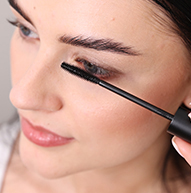 A woman skillfully uses a mascara brush to apply mascara