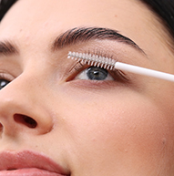 A woman uses a brush to apply mascara